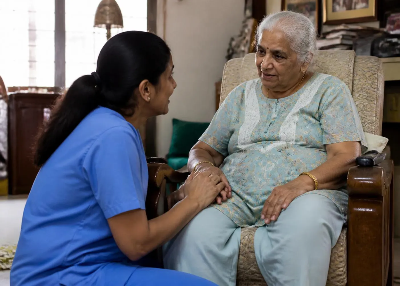 A daughter and a nurse together helping an elderly mother in her living room